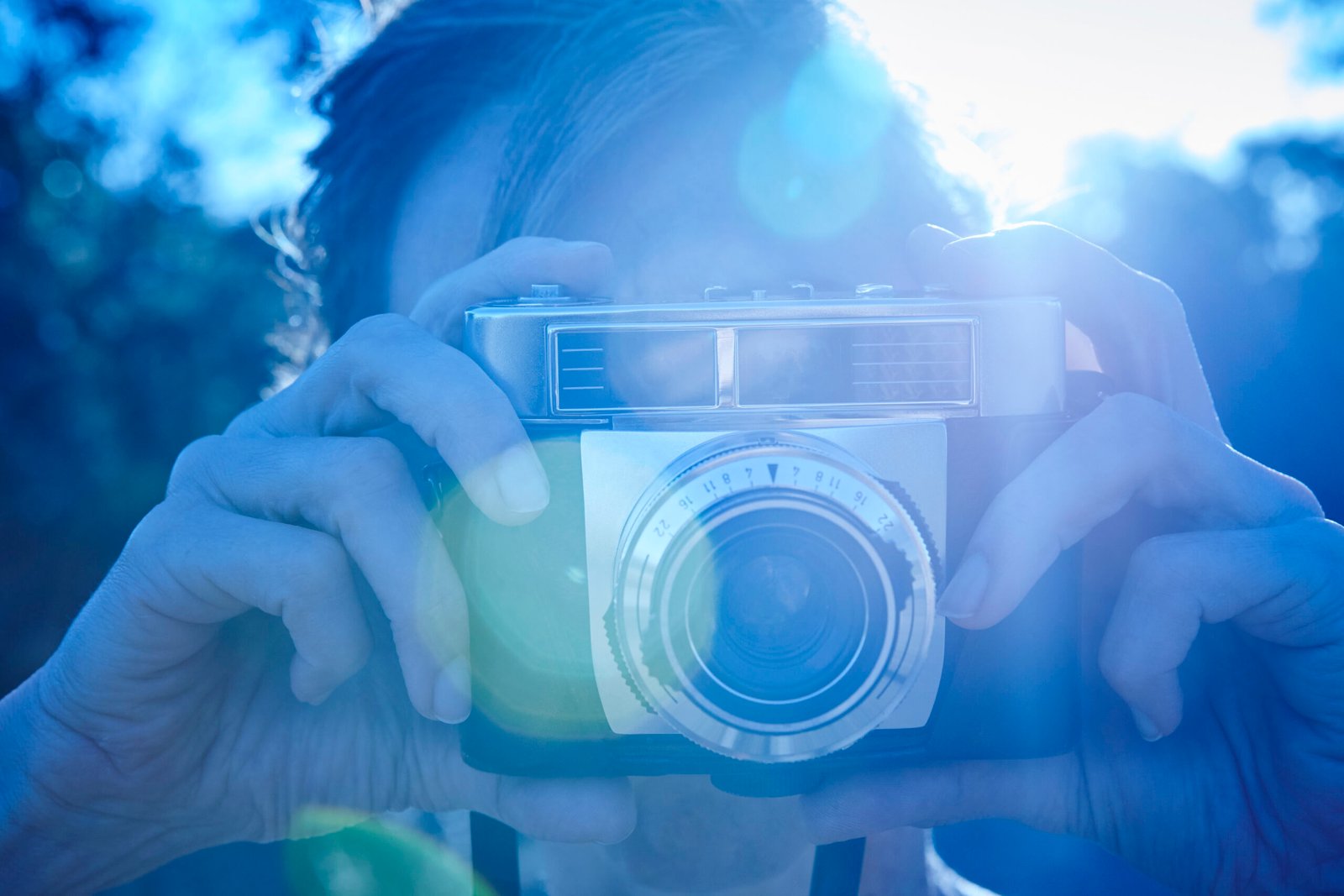 woman taking pictures with vintage camera. backlight. blue tone